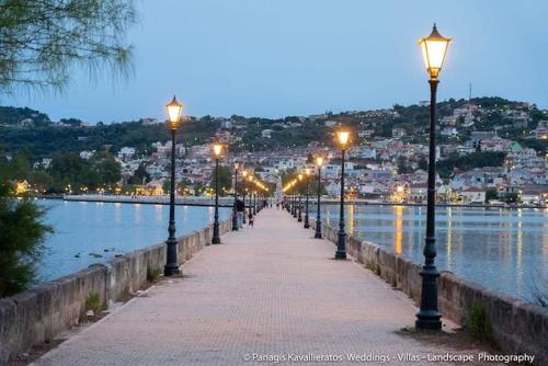 a row of street lights on a sidewalk next to the water at CityCenter Apartment in Argostoli