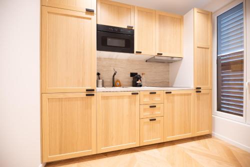 - une cuisine avec des placards en bois et un four micro-ondes dans l'établissement Stylish Flat in Paris' Center, à Paris