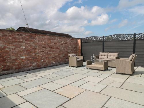 a patio with chairs and a brick wall at 1 The Stables in Highbridge
