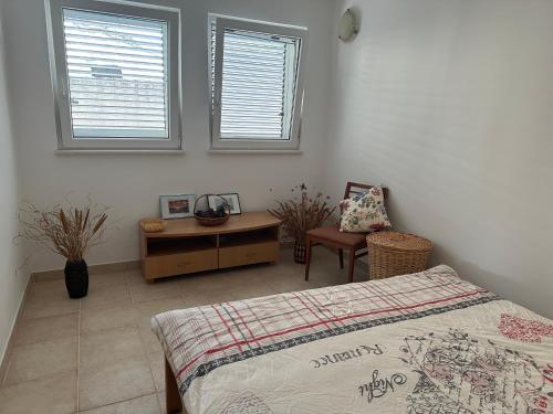 a bedroom with a bed and a desk and two windows at Kalina in Bigovo