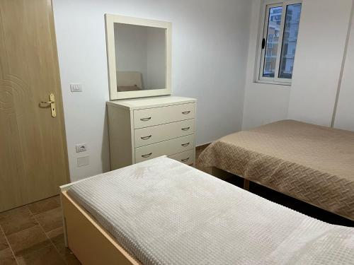 a bedroom with two beds and a dresser with a mirror at Al mare! 01 in Shëngjin