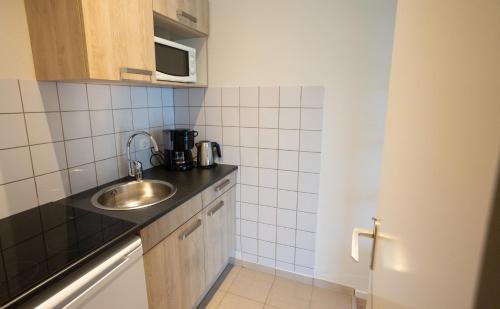 a small kitchen with a sink and a microwave at Holiday Park La Sapinière in Hosingen