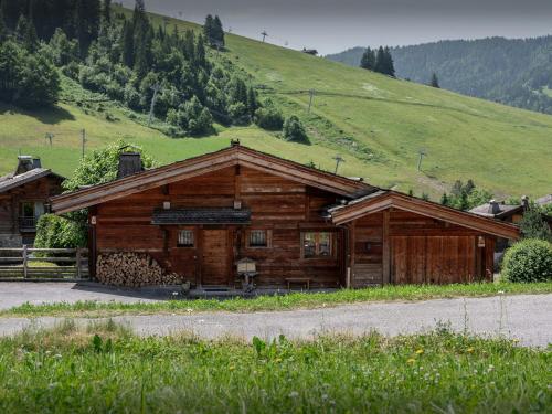 a wooden cabin with a green hill in the background at Chalet Le San Marco - OVO Network in La Clusaz