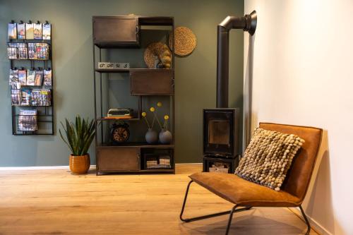 a living room with a chair and a book shelf at Thús yn Hantum in Hantum