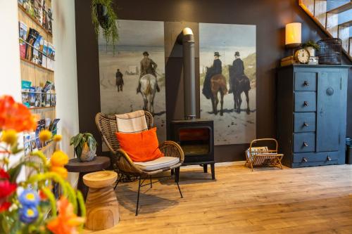 a living room with a fireplace and a chair with an orange pillow at Thús yn Hantum in Hantum