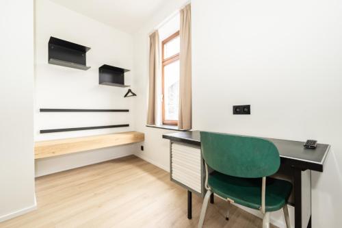 a room with a desk and a green chair at Hôtel de la Poste in Gedinne