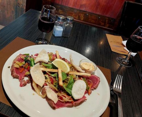 a white plate of food on a table with wine at Hôtel de la Poste in Gedinne