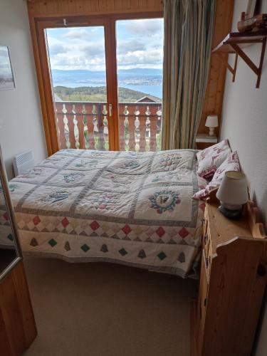 une chambre avec un lit et une grande fenêtre dans l'établissement LaPerdrixBlanche, à Thollon-les-Mémises