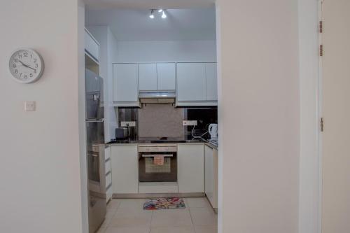 a kitchen with white cabinets and a clock on the wall at Elysia Park Apartments in Paphos City