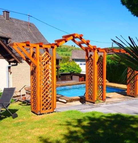 an orange pergola next to a swimming pool at Wellness-Ferienwohnung-EifelErnstbergblick 1 in Daun