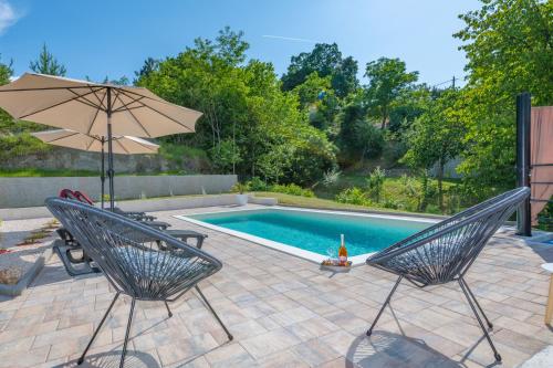 a swimming pool with two chairs and an umbrella at Villa Bonissa, a private and tranquil haven amidst nature in Pićan