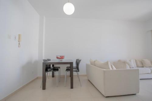 a white living room with a table and a couch at Elysia Park Apartments in Paphos City