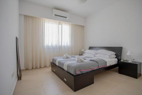 a bedroom with a large bed with white sheets and pillows at Elysia Park Apartments in Paphos City