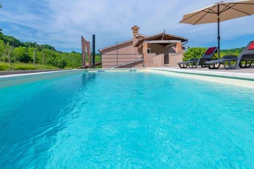 a swimming pool with blue water in front of a house at Villa Bonissa, a private and tranquil haven amidst nature in Pićan