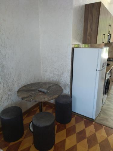 a table and stools in a kitchen with a refrigerator at White House Avtandil&Nino in Sarpi