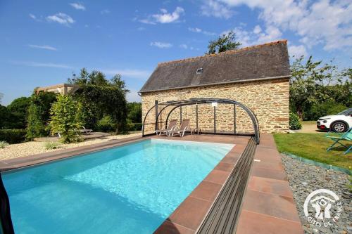 a swimming pool in front of a brick building at Le ruset in Saint-Donan