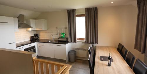 a kitchen and dining room with a wooden table at Holiday Park La Sapinière in Hosingen