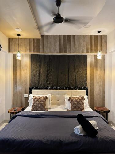 une chambre avec un grand lit avec une tête de lit noire dans l'établissement Dolally Pool and bar By villagram, à Lonavala