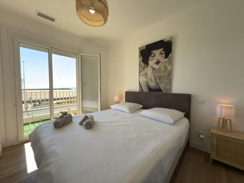 une chambre avec un grand lit blanc avec une grande fenêtre dans l'établissement Balcon sur la Mediterranee, à Valras-Plage