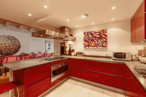 a kitchen with red cabinets and a counter top at Super Luxurious Duplex Penthouse in Gstaad Center in Gstaad