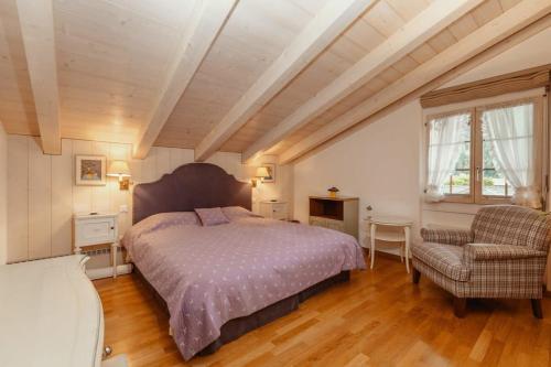 a bedroom with a large bed and a chair at Super Luxurious Duplex Penthouse in Gstaad Center in Gstaad