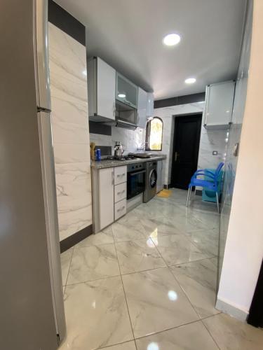 a kitchen with white cabinets and a tile floor at Complexe Al AMINE plage -rifiyine in Dar Merah Deriba