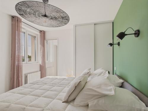 une chambre avec un grand lit avec des oreillers blancs dans l'établissement Vue rivière - Bel appartement avec balcon pour 8, à Saint-Gilles-Croix-de-Vie