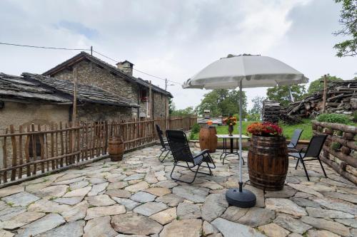 a patio with a table and chairs and an umbrella at La Mason dla Grà in Frassinetto