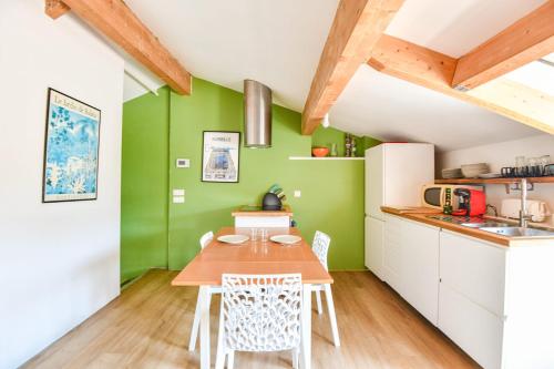 - une cuisine avec des murs verts, une table et des chaises en bois dans l'établissement Bel appart avec terrasse et vue sur Notre-Dame, à Marseille