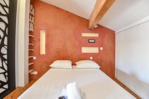 Ce lit se trouve dans une chambre dotée d'un mur rouge. dans l'établissement Bel appart avec terrasse et vue sur Notre-Dame, à Marseille