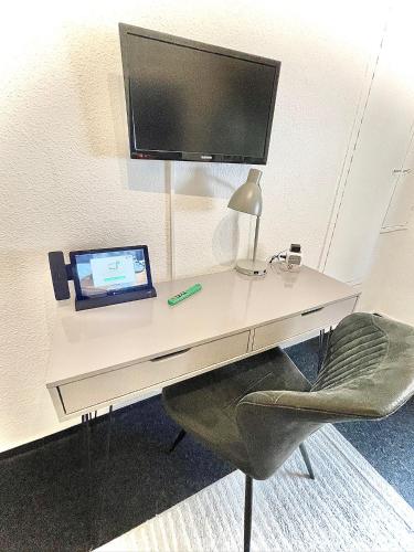 a desk with a computer and a monitor and a chair at Hotel Tusculum in Marburg an der Lahn