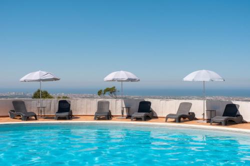 a swimming pool with lounge chairs and umbrellas at Sao Felix Hotel Hillside & Nature in Póvoa de Varzim