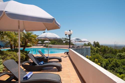 a row of chairs and an umbrella next to a swimming pool at Sao Felix Hotel Hillside & Nature in Póvoa de Varzim