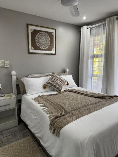 a bedroom with a white bed and a window at Rietjie Se Plekkie in Amanzimtoti