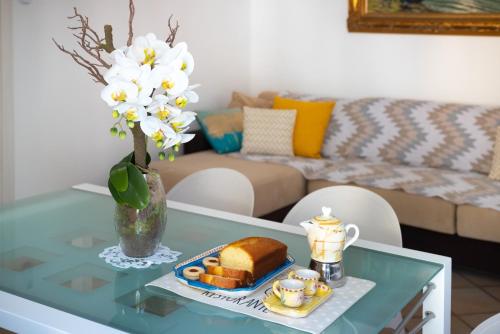 a glass table with a plate of bread and a vase with flowers at Casa Alice in Cetara