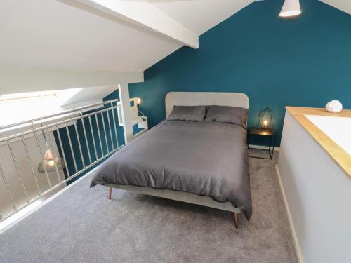 a bed in a room with a blue wall at Myrtle Loft in Keighley