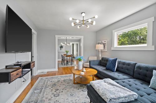 a living room with a blue couch and a flat screen tv at Newly Renovated 2BR by SU, Zoo, Destiny & Downtown in Syracuse