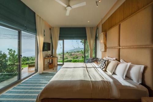 a bedroom with a large bed with a large window at SaffronStays Swallow's Nest in Kolvan