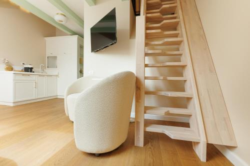 a living room with a white chair and a staircase at 1910 Boutique - Central, Scenic, Self Check-In in Braşov