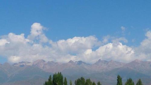 a view of a mountain range with clouds and trees at взморье in Bosteri