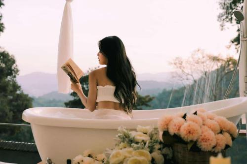 a woman sitting in a bath tub reading a book at ภูสกาย โฮมสเตย์ in Mon Jam