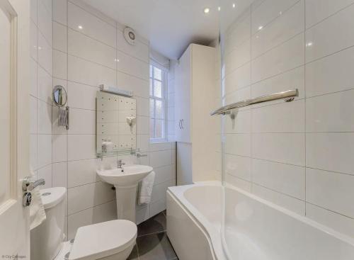 a white bathroom with a sink and a toilet and a tub at 4B City Cottages in Chester