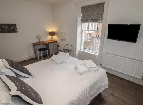 a bedroom with a white bed with two towels on it at 4A City Cottages in Chester