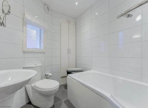 a white bathroom with a toilet and a sink at 4A City Cottages in Chester