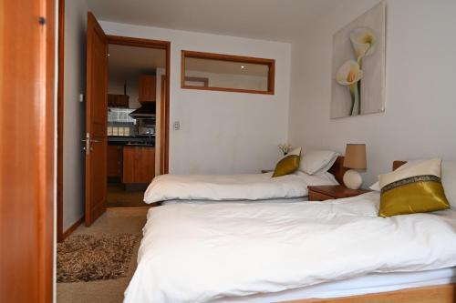 two beds in a room with white sheets and yellow pillows at Casa Farellones Lower Apartment in Farellones