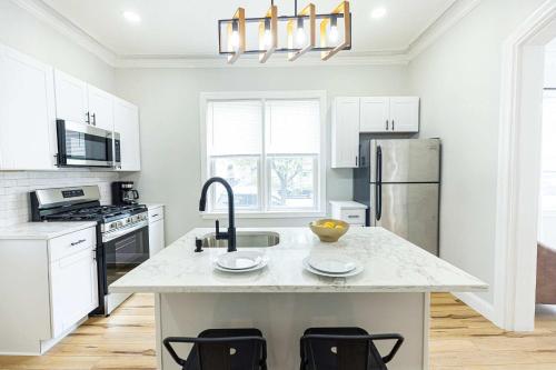 a white kitchen with a sink and a refrigerator at Jennifer's Spa-Like Apt King Bed Historic Broadway in Providence