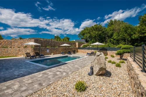 a swimming pool with two umbrellas and a patio at Kuća za odmor TARA & LANA I in Kornić