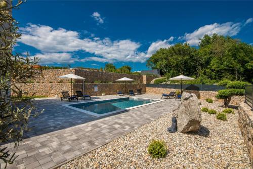 a swimming pool with umbrellas and a stone wall at Kuća za odmor TARA & LANA I in Kornić