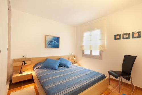 a bedroom with a bed with blue pillows and a chair at Gruat 31 - Vallem Properties in Pollença