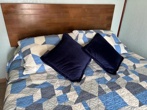 a bed with two black pillows on it at Primavera y dias de sol en Cabaña Roscoe's Paradise Playa Los Molles- 2 -3 personas in Los Molles